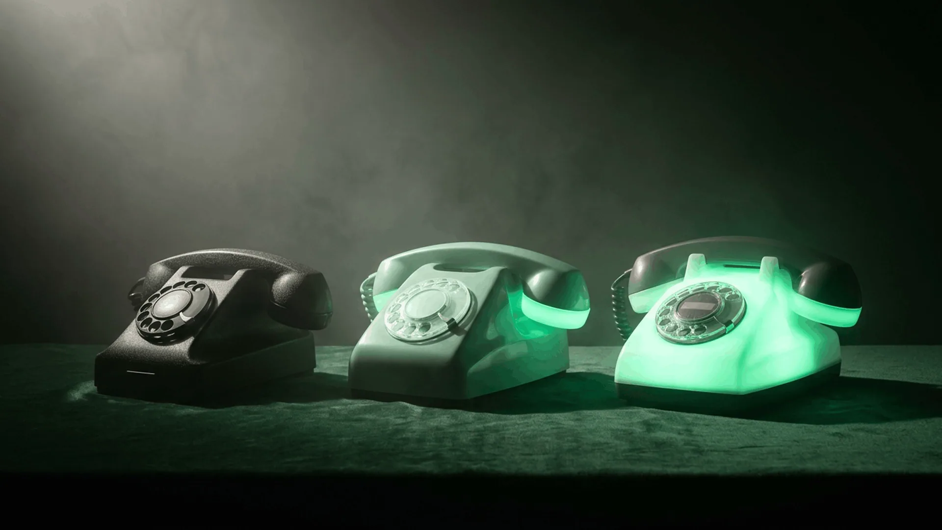 Voicebot vs. IVR vs. Live Agent: A Comparison Guide for Healthcare Practices Cinematic product render of three vintage rotary telephones on a deep green velvet surface, progressing left to right from matte black to pale gray to fully glowing mint green, representing the capability progression from IVR to live agent to AI voicebot for healthcare patient access