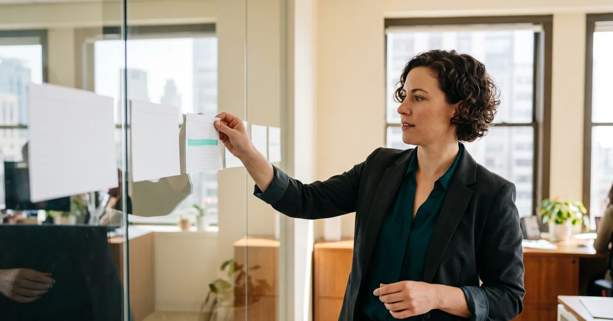 Healthcare operations leader arranging patient access workflow cards on a glass planning board