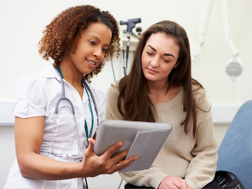 A patient and a healthcare professional look at something on a tablet together